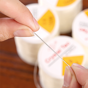 TRIXES Clear Elastic Spool between someone's fingers to show the thickness of the cord